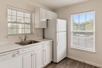 a kitchen with white cabinets and a sink and a refrigerator